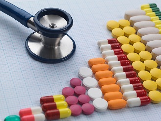 Variety of medicine and stethoscope on graph paper to illustrate increase in medical drug use