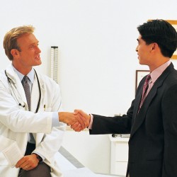 Doctor and businessman shaking hands in clinic